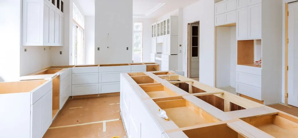 New kitchen under construction with white shaker cabinets, large island base, and unfinished countertops – custom cabinetry installation by Floor & More in Centennial, CO
