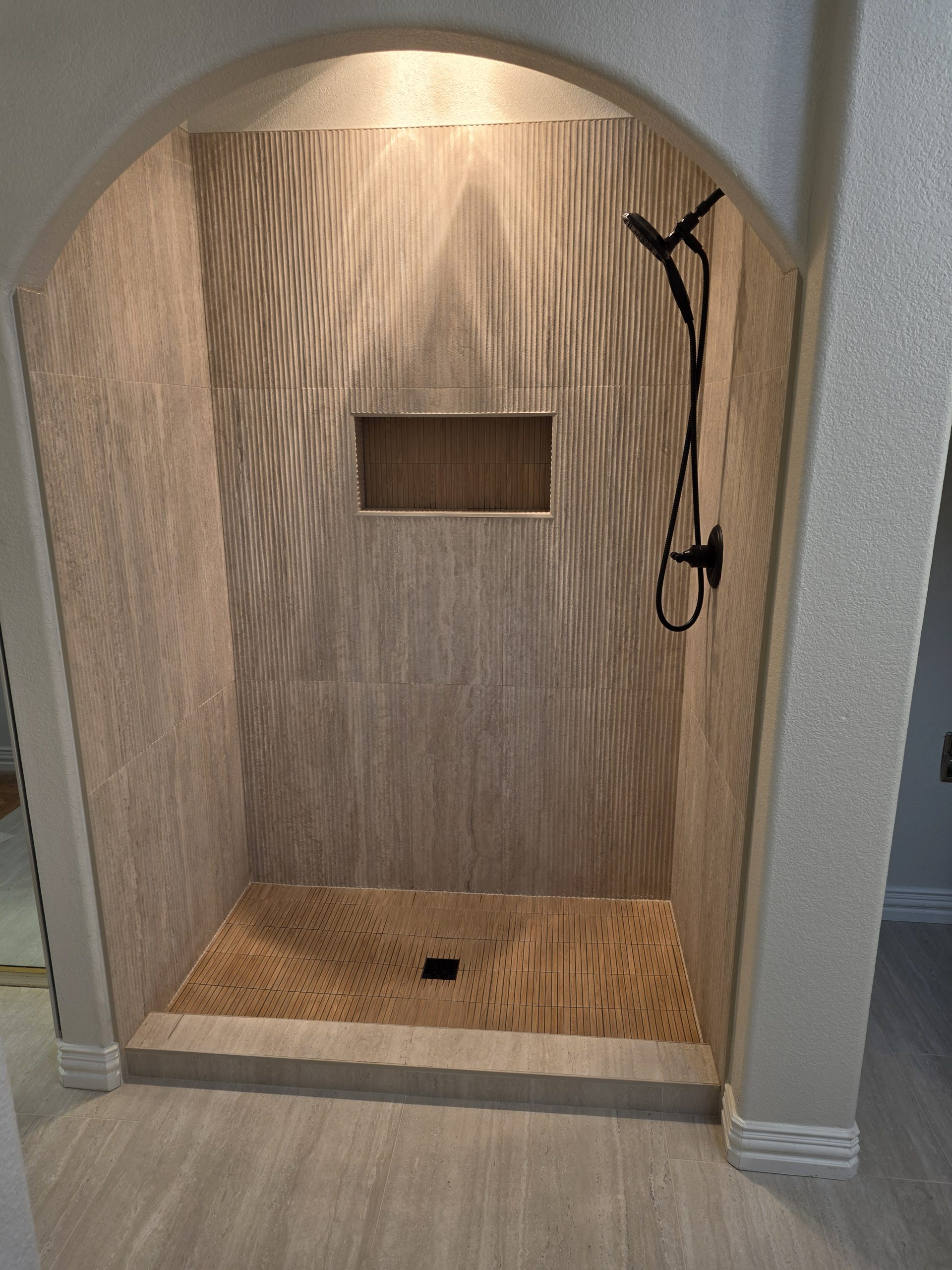 Large-format travertine-look wall tile and plantation shutters in a Highlands Ranch, CO master bathroom