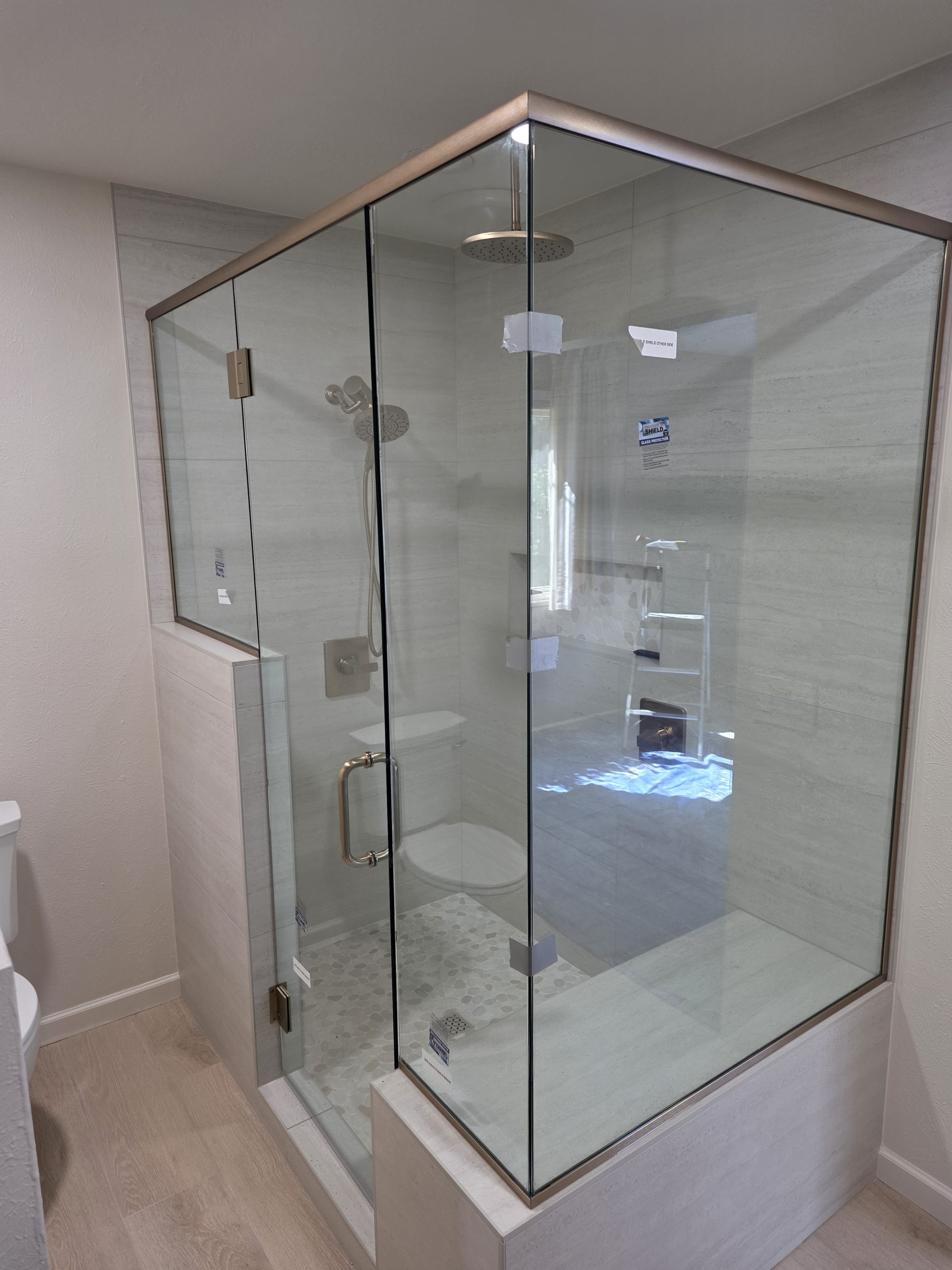 Frameless glass shower door and wood-look plank flooring in a completed Littleton, CO bathroom remodel