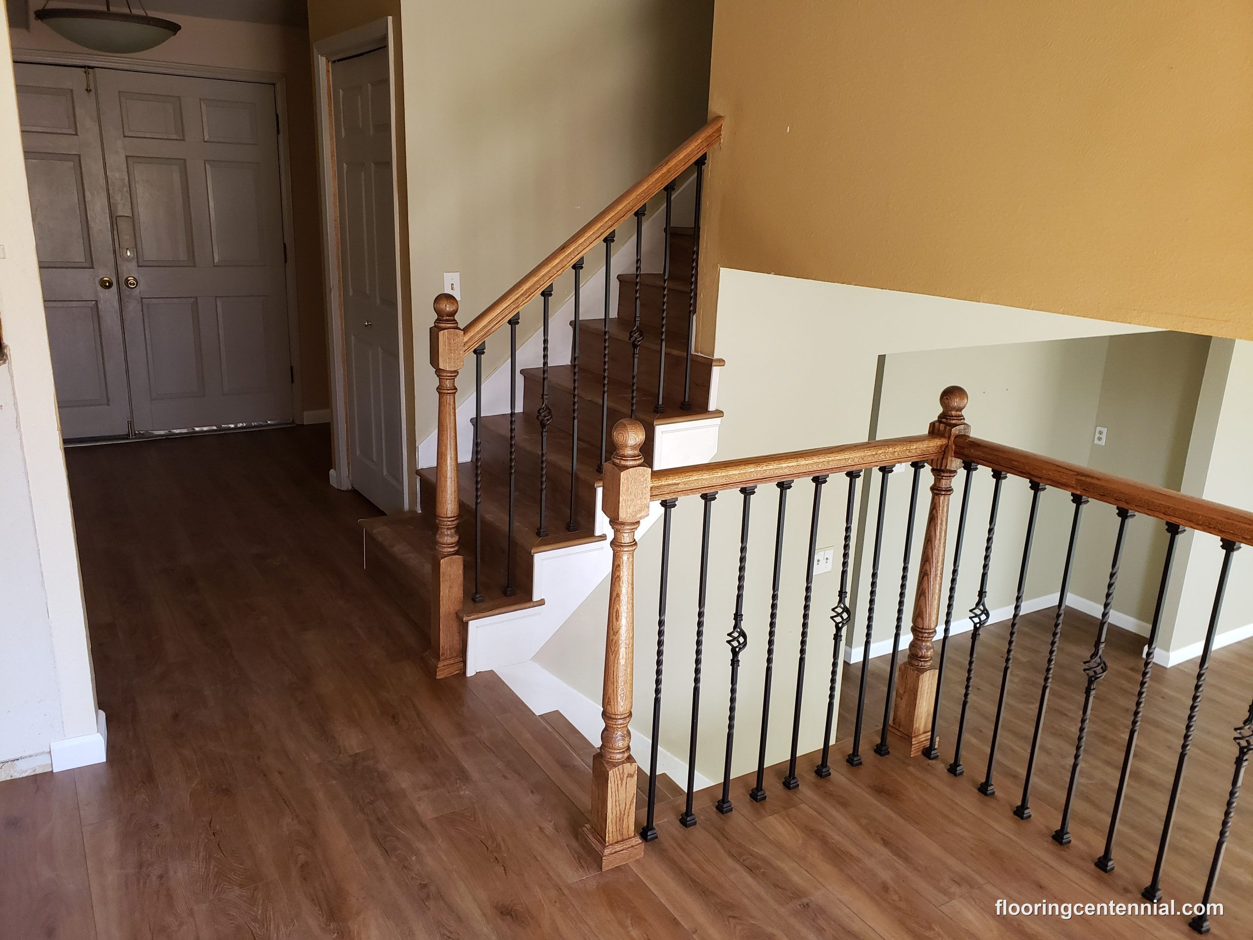 Home entryway staircase with oak railing and hardwood-look flooring