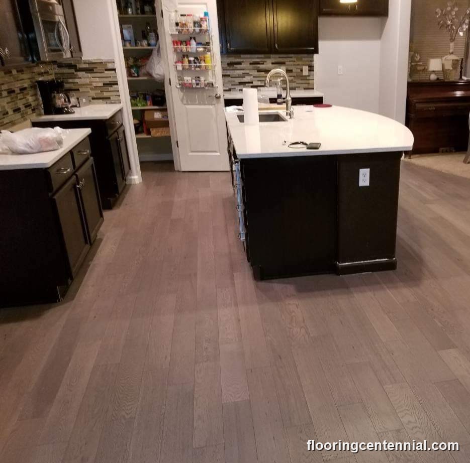 Kitchen with white cabinetry, island, and gray-toned hardwood flooring