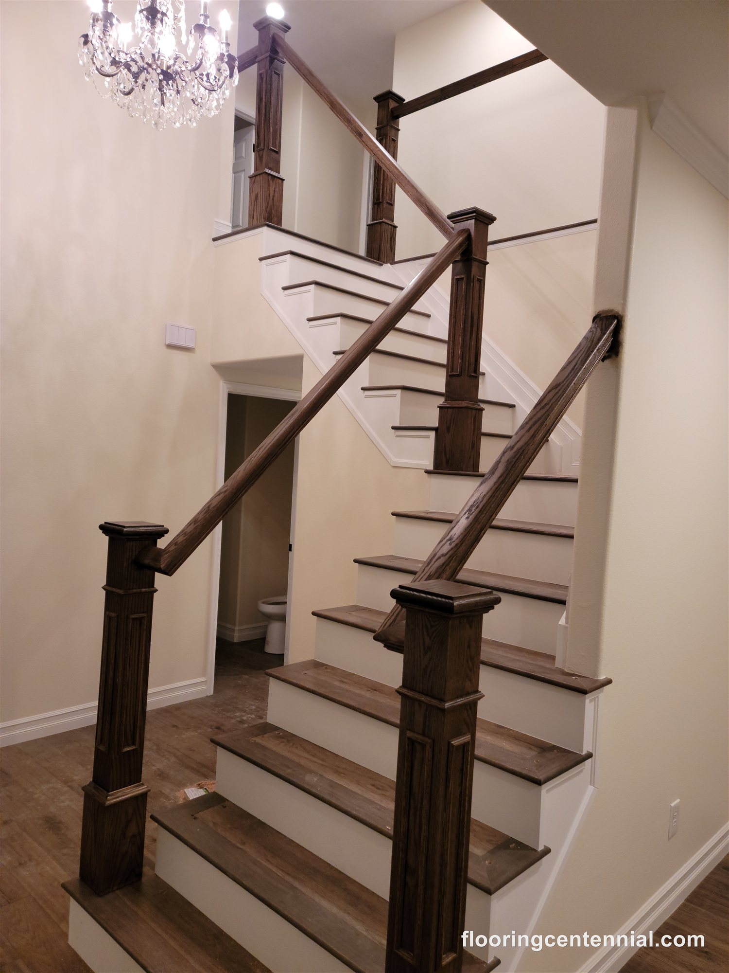 Two-story staircase with dark stained hardwood treads and crystal chandelier