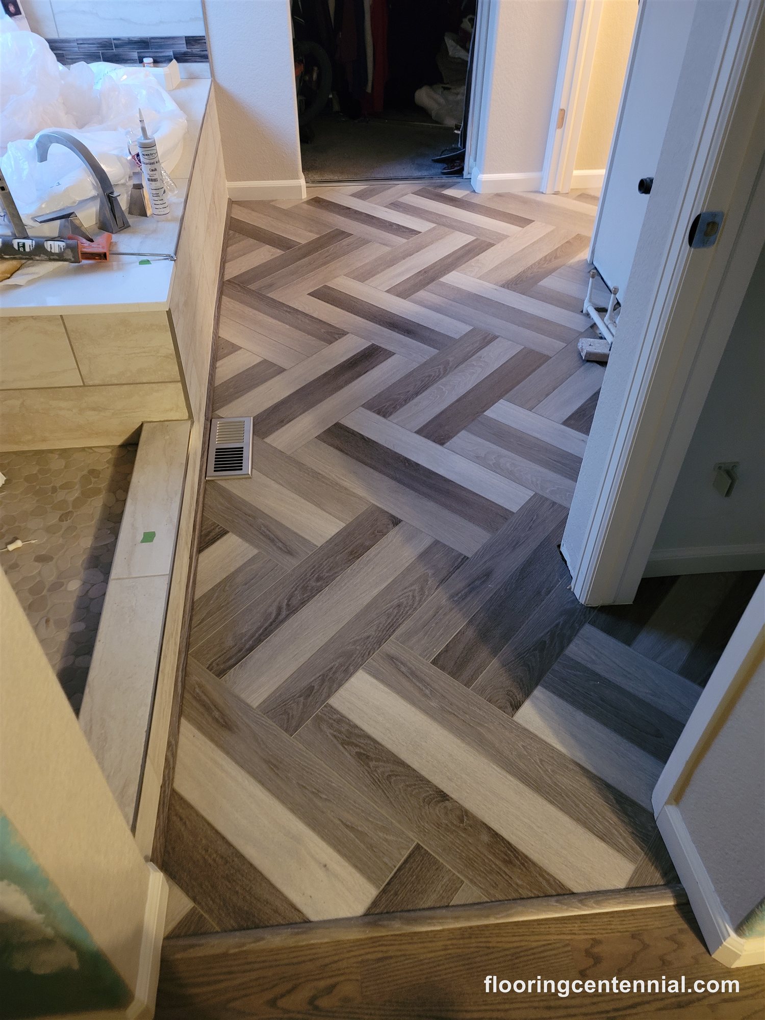 Herringbone pattern wood-look tile flooring installed in a bathroom