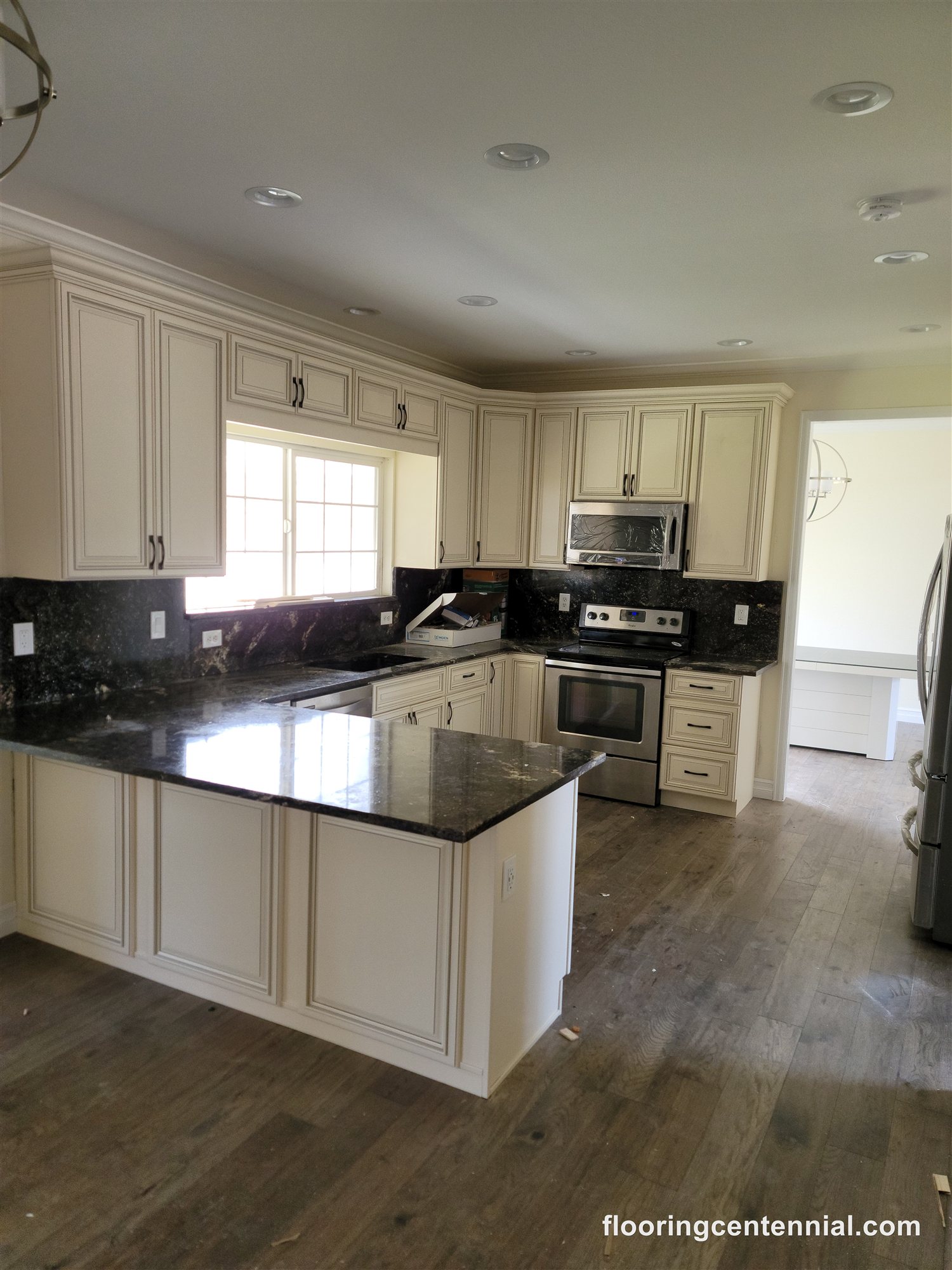 Kitchen with cream cabinetry, dark granite counters, and hardwood flooring