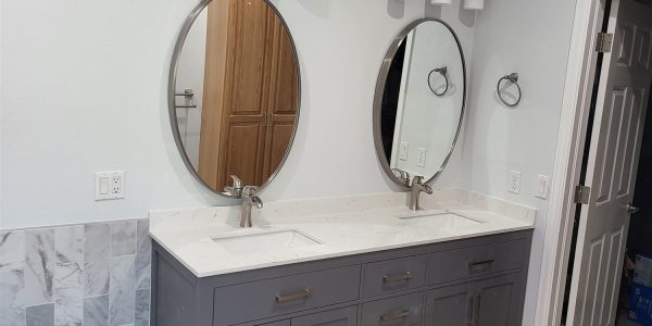 Double vanity bathroom remodel with oval mirrors and tile flooring