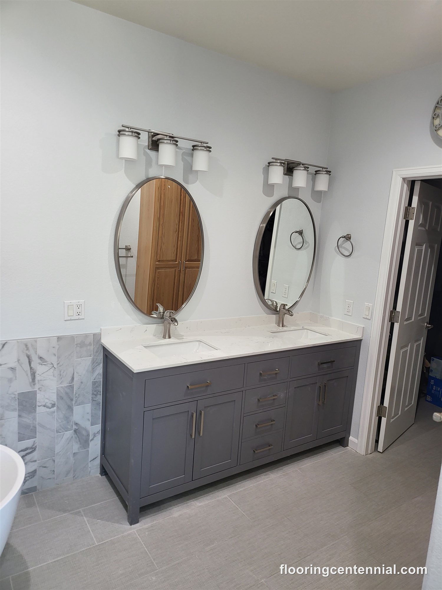 Double vanity bathroom remodel with oval mirrors and tile flooring