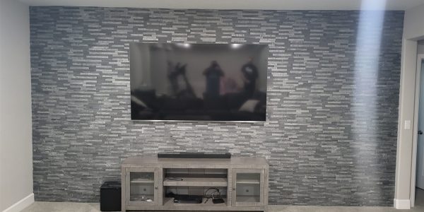 Dark slate stacked stone accent wall with mounted TV