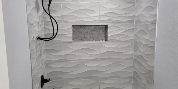 Bathroom shower with dimensional wave-pattern tile surround and black fixtures