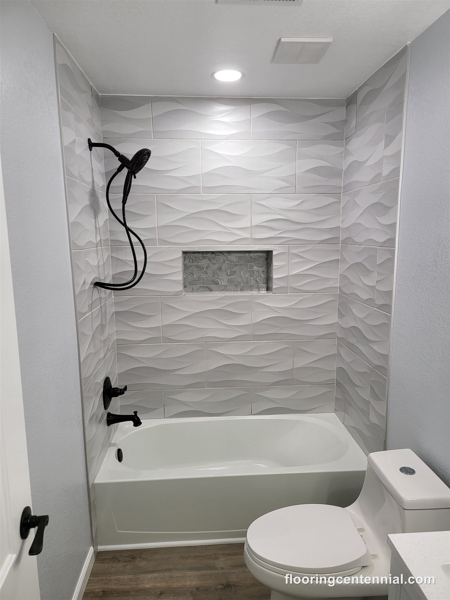 Bathroom shower with dimensional wave-pattern tile surround and black fixtures