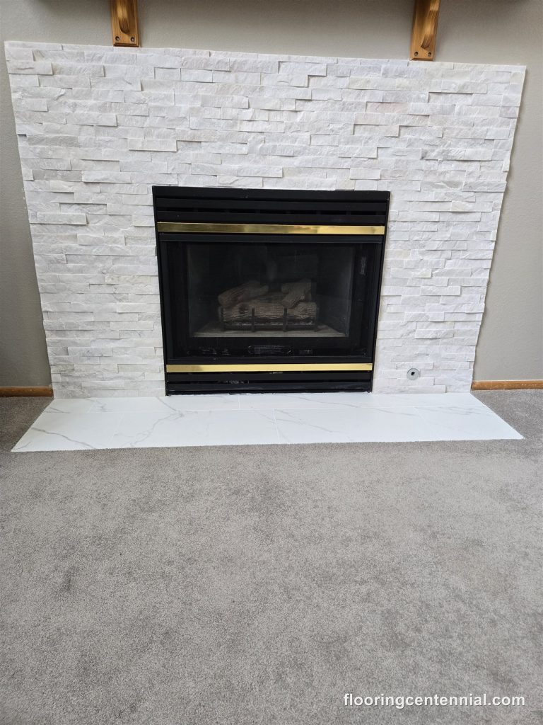 White stacked stone fireplace with brass trim insert and marble hearth