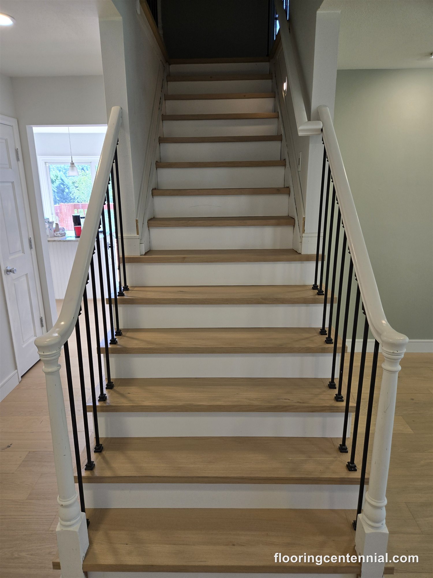 Refinished oak staircase with black iron balusters and white risers
