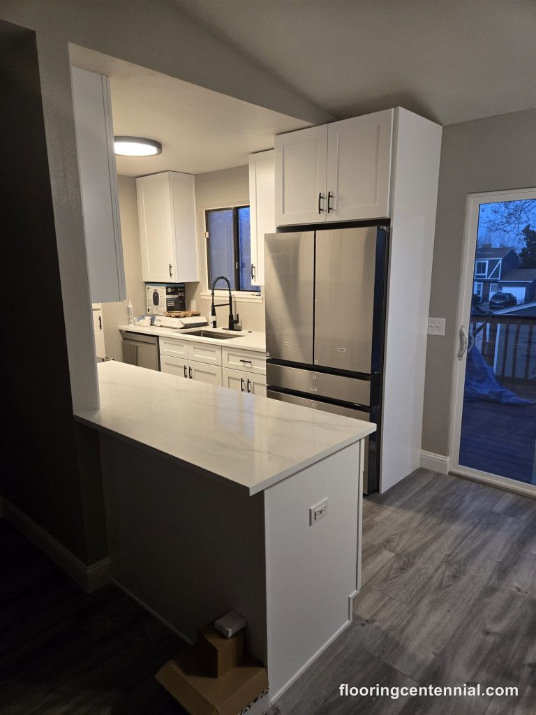 Kitchen remodel with new white shaker cabinets, quartz peninsula and LVP flooring in Aurora, CO