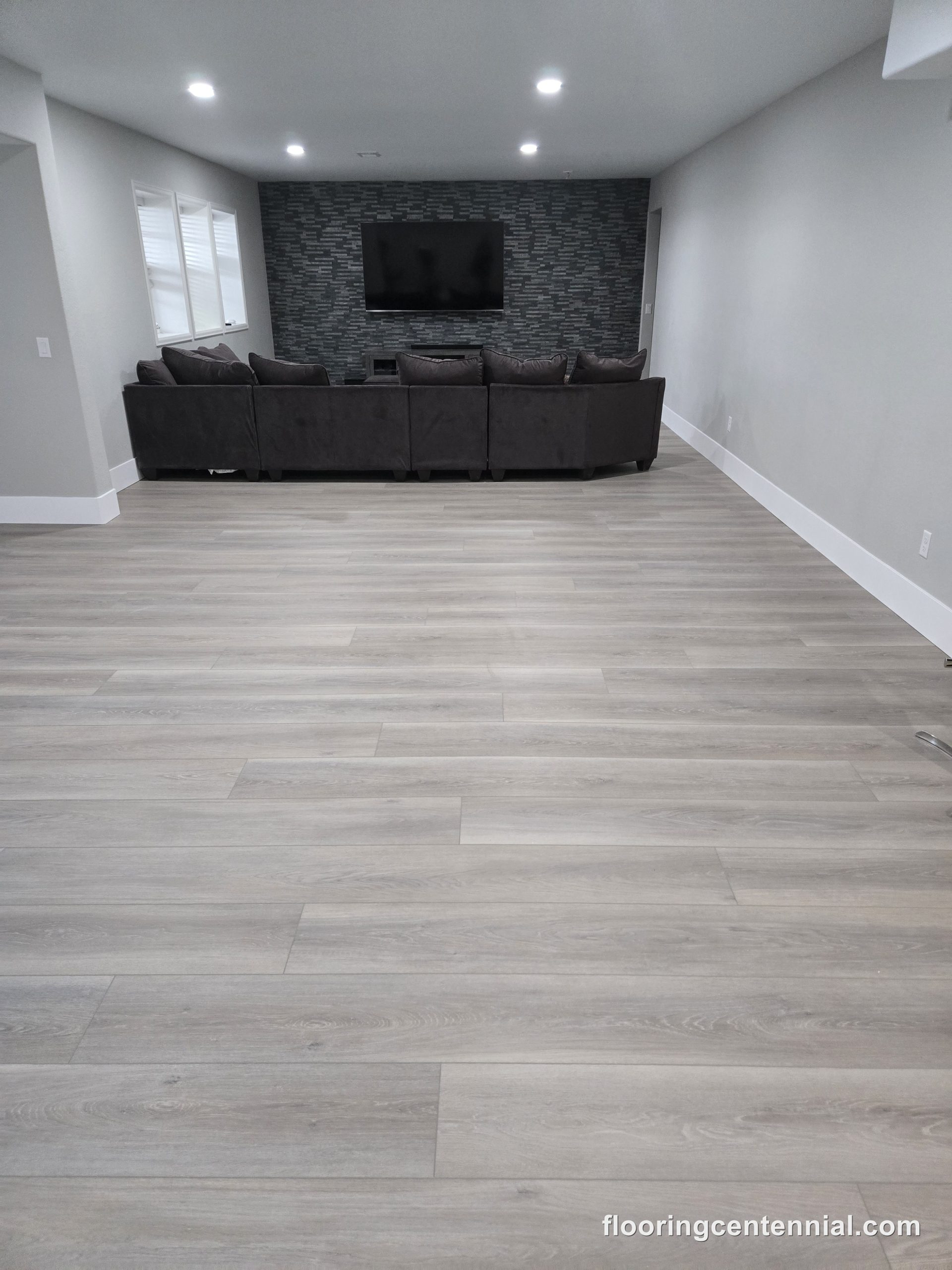 Living/media room with wide-plank gray luxury vinyl flooring
