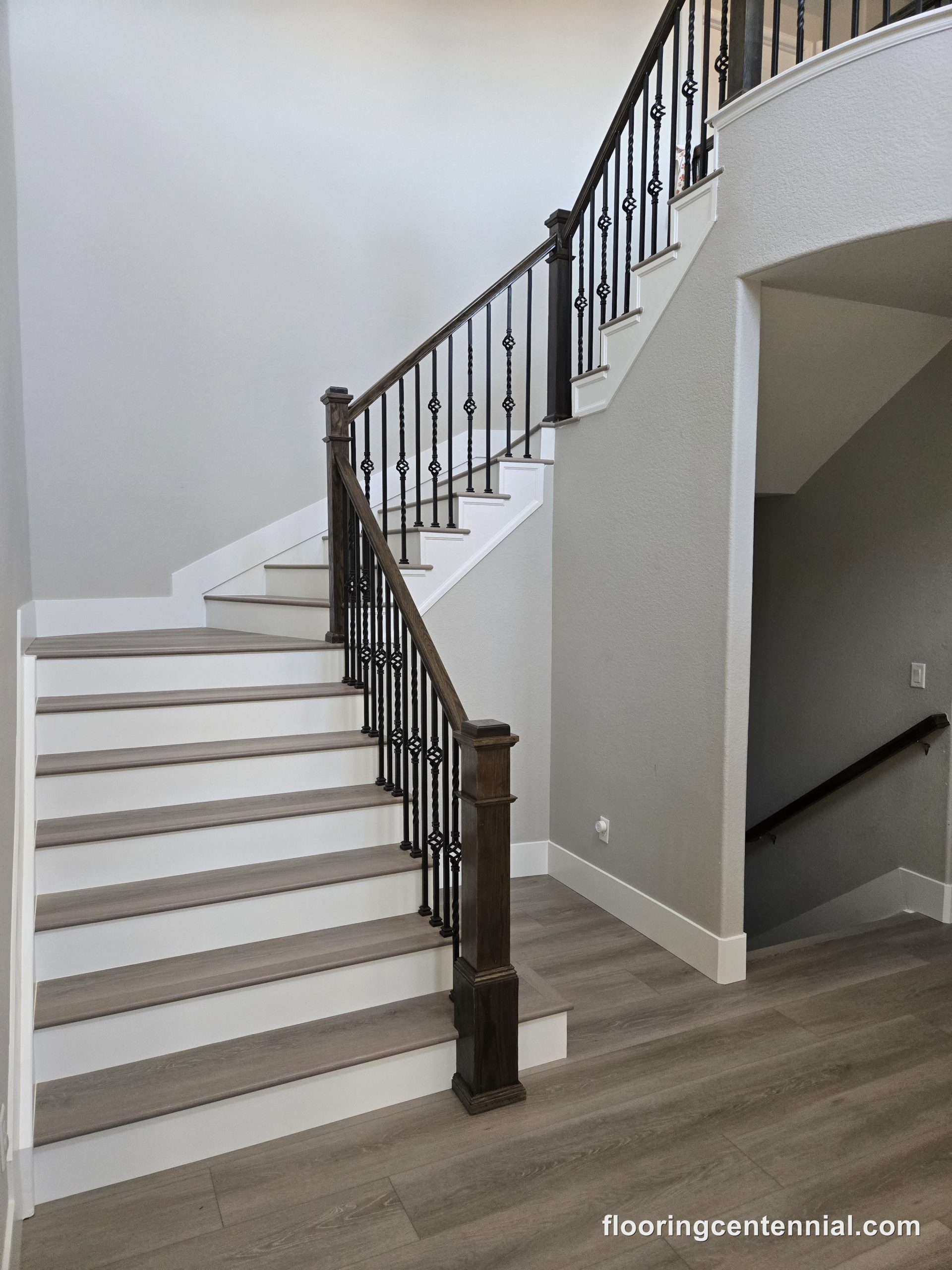 Staircase with wood-look flooring and wrought iron railing